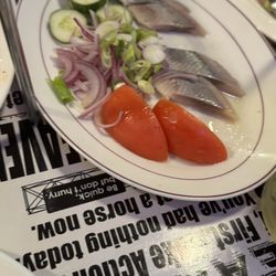 Marinated herring served with fresh cucumber slices, tomato wedges, red onion, and scallions.