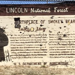 Smokey Bear Motel - Exterior: weathered origin sign adjacent to park