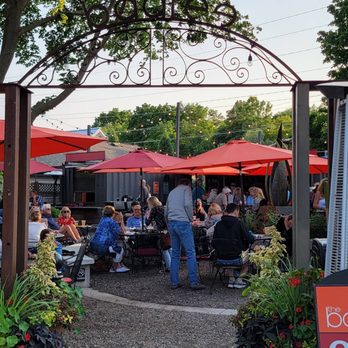 the baaree - a group of people sitting at tables under red umbrellas - New American Near Me - Thiensville, Wisconsin