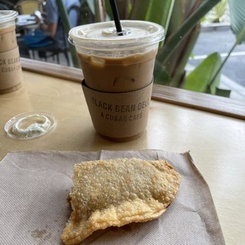 Black Bean Deli - Iced coffee with oat milk and half eaten chicken empanada - Cuban Near Me - Winter Park, Florida Black Bean Deli - Iced coffee with oat milk and half eaten chicken empanada - Cuban Near Me - Winter Park, Florida