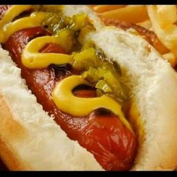 a hot dog and french fries - A close-up image of a hot dog in a bun, topped with mustard and relish, accompanied by a serving of French fries. The hot dog is placed on a paper-lined tray, highlighting typical fast-food presentation.