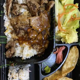 a bento box with rice, meat and vegetables
