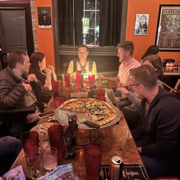 a group of people sitting around a table eating pizza a group of people sitting around a table eating pizza