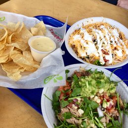 A pork bowl and a chicken bowl with chips and queso