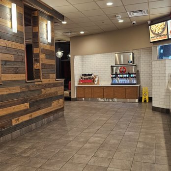 Arby's - A fast-food restaurant interior featuring a beverage station with soda dispensers, digital menu screens, and a counter for online order pickup. - Fast Food Near Me - Gilbert, Arizona