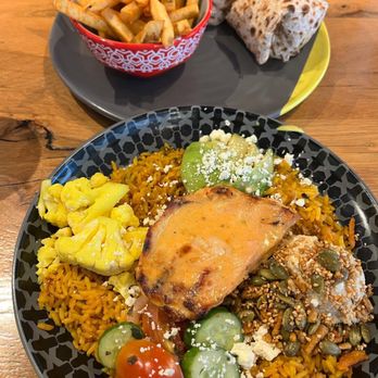 Nando's Peri-Peri - PERi Chicken Rainbow Bowl with a Spicy Chicken Caesar Wrap and chips in the background - South African Near Me - Skokie, Illinois