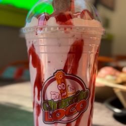 Strawberry milkshake with strawberry, drizzle, bananas, and sprinkles