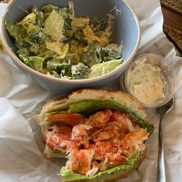 Lobster roll and ceasar salad. Already partially eaten. Lobster roll and ceasar salad. Already partially eaten.