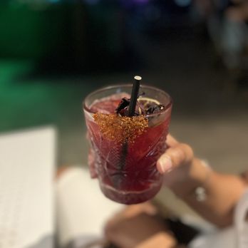 Soho Garden - a woman holding a glass of cocktail - Cocktail Bars Near Me - Houston, Texas