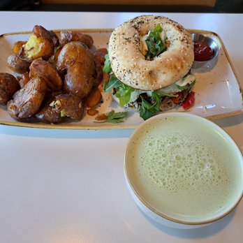 Everly - Confit Pork Bagel Breakfast Sandwich with fingerling potatoes and blueberry matcha latte. - New American Near Me - Madison, Wisconsin