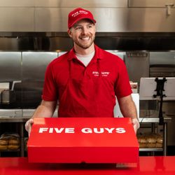 Five Guys - A Five Guys employee holds the red Five Guys catering box at the counter.