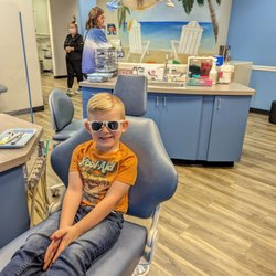 Camelback Pediatric Dentistry & Orthodontics - All smiles while sitting in the motorized chair with fun sunglasses.