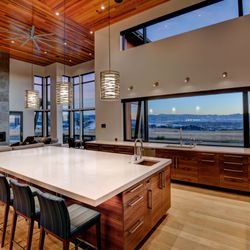 Custom kitchen  and living room lighting with layered design: hanging island lights, wall accents, and recessed ceiling illumination.