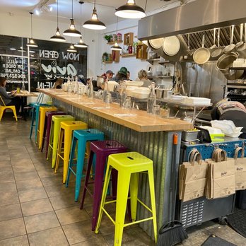 Aviv Hummus Bar - a view of a kitchen with colorful stools - Falafel Near Me - Seattle, Washington Aviv Hummus Bar - a view of a kitchen with colorful stools - Falafel Near Me - Seattle, Washington