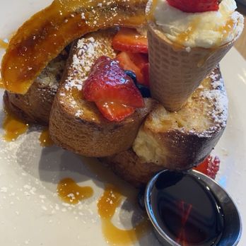 Hash Kitchen - Banana Split Brioche French Toast - French toast with strawberries, whipped cream, caramel sauce, and a strawberry ice cream cone on top, served with syrup. - New American Near Me - Gilbert, Arizona