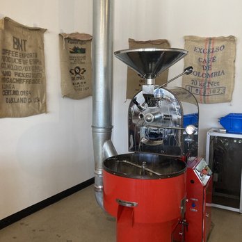 Tre Stelle Coffee - Large coffee bean roasting machine with empty burlap coffee bean bags hanging on the wall. - Coffee & Tea Near Me - Dallas, Texas Tre Stelle Coffee - Large coffee bean roasting machine with empty burlap coffee bean bags hanging on the wall. - Coffee & Tea Near Me - Dallas, Texas