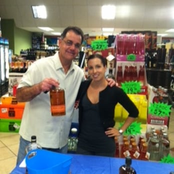 Broadway Liquors - a man and a woman standing in front of a table with bottles of liquor - Beer, Wine & Spirits Near Me - Lawrence, Massachusetts