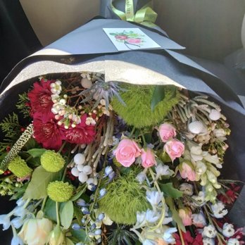 bōtan - The Anaïs - A floral arrangement with pink roses, red dahlias, white and blue flowers, and greenery, placed on a car seat with a card and ribbon. - Florists Near Me - Buffalo, New York