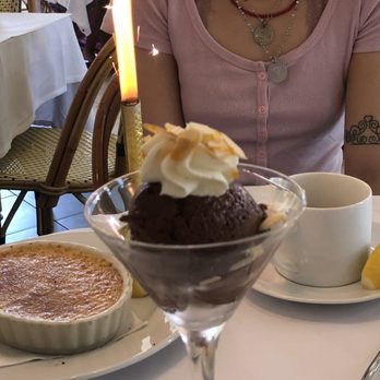Le Bilboquet - a woman sitting at a table with a dessert - French Near Me - Dallas, Texas Le Bilboquet - a woman sitting at a table with a dessert - French Near Me - Dallas, Texas