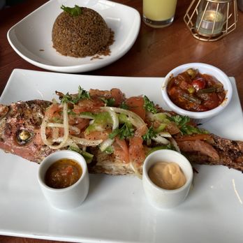Spicy Water African Grill - Grilled snapper - simply and mouthwateringly, delightfully flavorful - cannot wait to go back! On the left side, traditional hollow rice! - African Near Me - Washington, DC, District of Columbia
