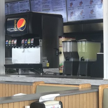 Jester's Fast Food - Fountain drinks available - A soda fountain with Pepsi branding and drink dispensers are positioned behind a counter at Jester's Fast Food, with menu boards visible above. - Fast Food Near Me - Elgin, Illinois