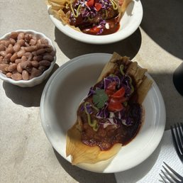 Side of blue corn tamal, side of jackfruit tamal and side of beans Side of blue corn tamal, side of jackfruit tamal and side of beans