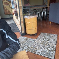 QDOBA Mexican Eats - Trash can overfilled while guy at counter is on phone