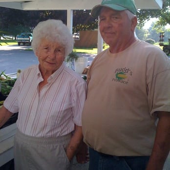 Budd's Produce - a man and a woman standing under a canopy - Farmers Market Near Me - Belleville, Michigan