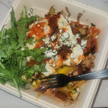 First Watch - So good I forgot to take a pic before I started eating. One of my favorite meals I have gotten here. - A disposable takeout container contains a partially eaten meal featuring fresh arugula greens on one side, and cooked ingredients such as eggs, sauce, and diced vegetables or meat. A black plastic fork is placed inside the container, and some food remnants are visible. The container is on a light-colored surface with some crumpled tissues nearby. - Breakfast & Brunch Near Me - Phoenix, Arizona