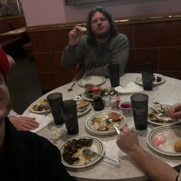 three men sitting at a table with plates of food