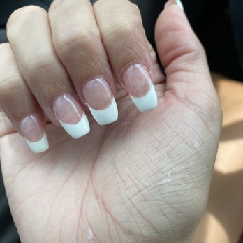 Nice Nails & Spa - A hand with a French manicure is shown, with some nails fully painted and others in progress, in a nail salon setting. - Nail Salons Near Me - Phoenix, Arizona