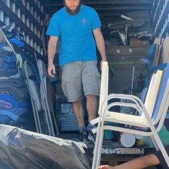 Integrity Moving - Loading Up! - A man with a beard, wearing a blue t-shirt, shorts, and a cap, is inside a moving truck filled with packed belongings and furniture. - Movers Near Me
