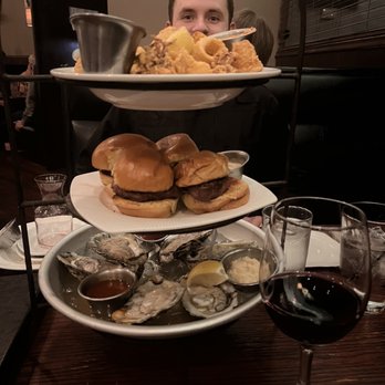 Stevens' -  a man sitting at a table with three plates of food and a glass of wine - American Near Me - Gurnee, Illinois