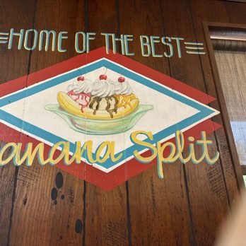 Andy's Igloo - A colorful painted sign on a wooden wall reads 'Home of the Best Banana Split' with an illustration of a banana split dessert. - American Near Me - Winter Haven, Florida