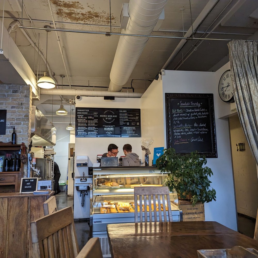 Counter with restaurant's staff as well as a couple of rows of tables with seating.