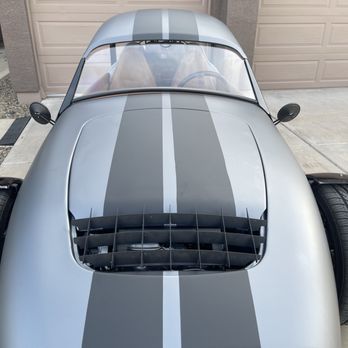 M Square Wraps - Front view - A silver sports car with black racing stripes is parked in a driveway in front of a garage door, viewed from above. - Vehicle Wraps Near Me - Mesa, Arizona