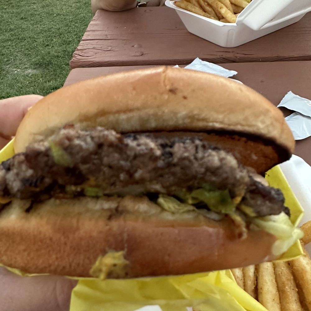 a hand holding a hamburger and french fries a hand holding a hamburger and french fries
