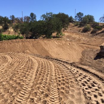 Wallis Excavating - a dirt field with tracks in it - General Contractors Near Me