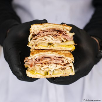 Bodega Cuban Kitchen - a person holding a sandwich - Food Trucks Near Me - Denver, Colorado