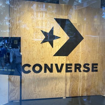 Converse Chicago Popup - The image shows a large Converse logo with a star and arrow on a wooden wall inside a store window, with reflections of the street outside. - Shoe Stores Near Me - Chicago, Illinois