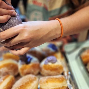 ResQ Bakery - a person grabbing a donut from a tray - Desserts Near Me ResQ Bakery - a person grabbing a donut from a tray - Desserts Near Me