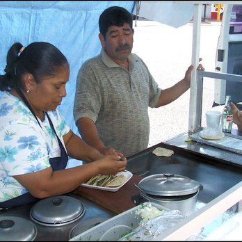 Chapa - Wife assembling tacos de barbacoa, as hubby looks on, with one tortilla still toasting on the griddle. - Tacos Near Me - Ciudad Miguel Alemán, TAM