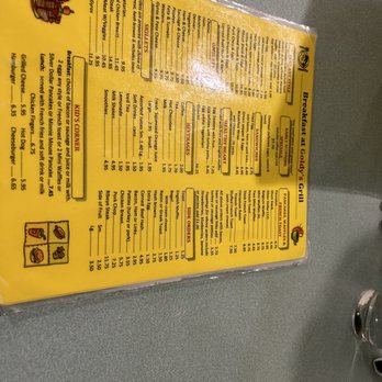 Goldy's Grill - Menu - A yellow-colored breakfast menu from Goldy's Grill in Park Ridge, IL, displays various food and beverage options, including breakfast items, sandwiches, beverages, side orders, and kids' menu. The menu features sections with item names, descriptions, and prices, along with small icons indicating different categories. The menu is printed on paper and appears to be part of a casual dining setting. - American Near Me - Park Ridge, Illinois