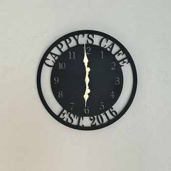 Cappy's Breakfast Cafe - Nice Clock, set 2016 and still going strong. Everyone gives her clocks for some reason. Take her one. - A black, round wall clock with cut-out text 'HAPPY'S CAFE' at the top and 'EST. 2016' at the bottom, mounted on a plain, light-colored wall. - Breakfast & Brunch Near Me - Tucson, Arizona
