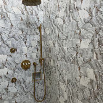 AR Remodeling Group - a marble shower - A shower area with marble tiles, featuring a gold rainfall showerhead, a handheld shower, and multiple control knobs. - General Contractors Near Me - Chicago , Illinois