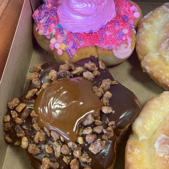 Tim Hortons - Caramel pecan donut - A box contains various donuts, including one with pink frosting and sprinkles, and another with chocolate glaze and caramel topping. - Coffee & Tea Near Me - Syracuse, New York