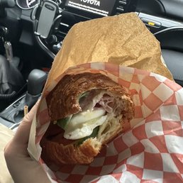 a person holding a croissant sandwich