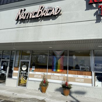 Native Bread - Native Bread bakery storefront features a sign, holiday plants, and a rainbow flag, with windows displaying product labels and business hours. - Bakeries Near Me - Indianapolis, Indiana