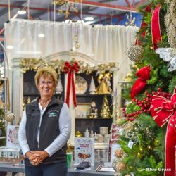 Blue Grass - Blue Grass employee standing in front of a Christmas Tree