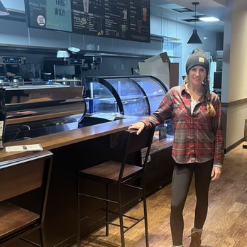 Aroma Joes - Middleton - a woman standing in front of a counter - Coffee & Tea Near Me - Middleton, Massachusetts Aroma Joes - Middleton - a woman standing in front of a counter - Coffee & Tea Near Me - Middleton, Massachusetts